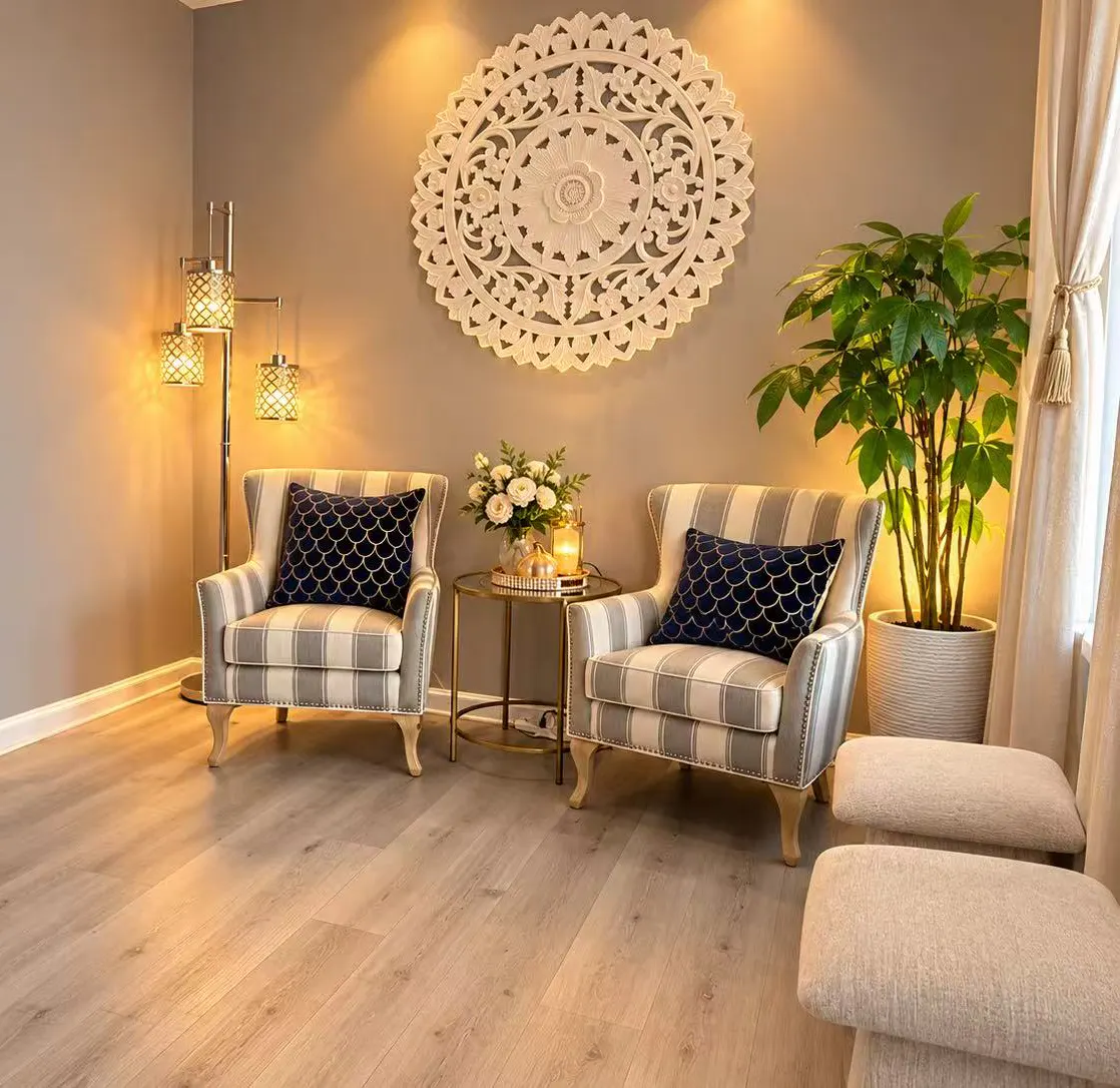 Reception lounge with two striped armchairs, a gold side table and a carved wall medallion
